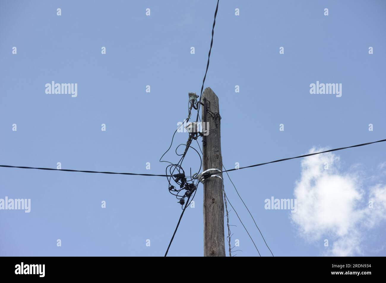 Un vecchio palo elettrico di legno con cavi elettrici appesi ad esso. Primo piano Foto Stock