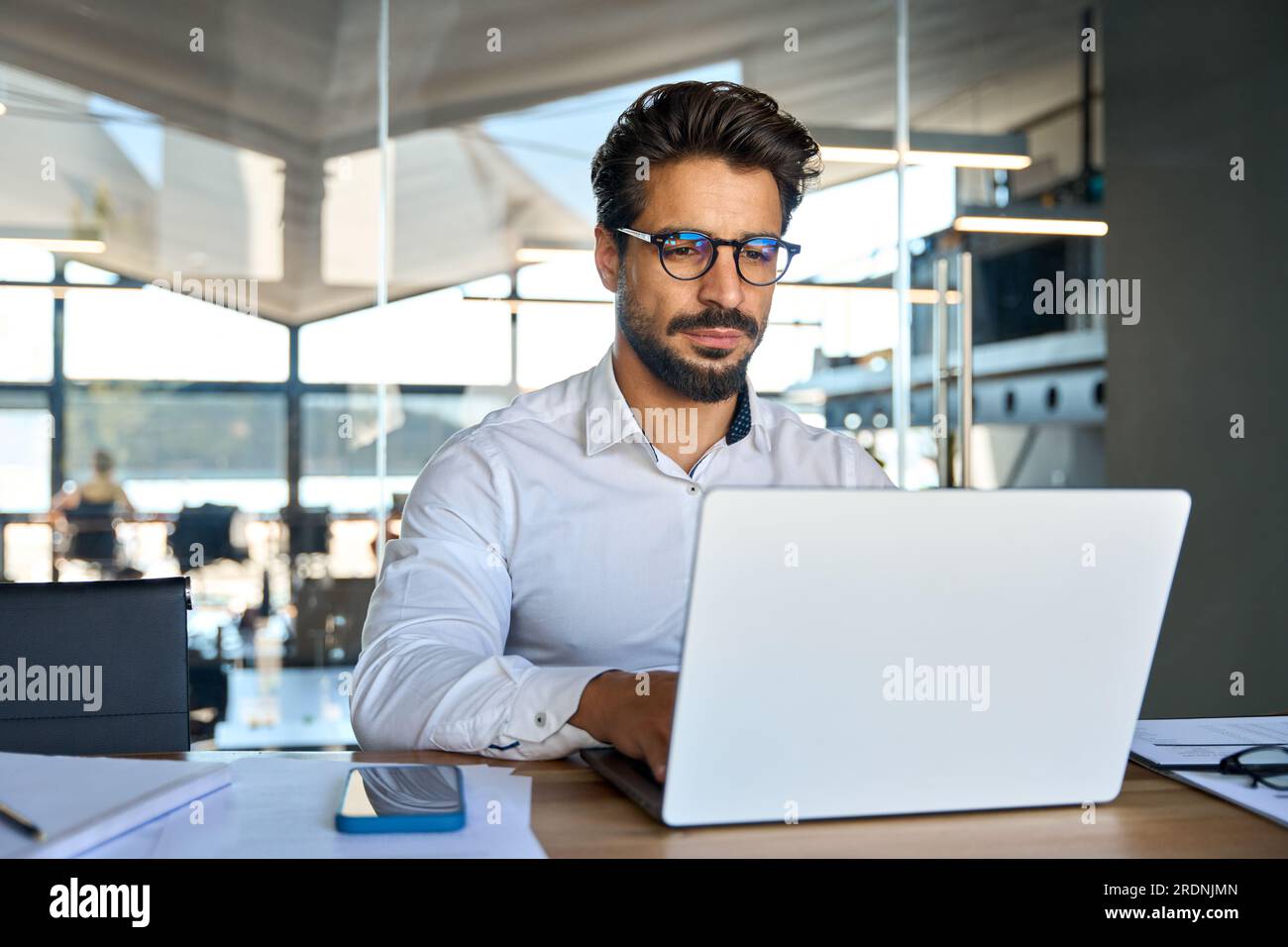 Giovane uomo d'affari serio che lavora con un computer portatile in ufficio. Foto Stock