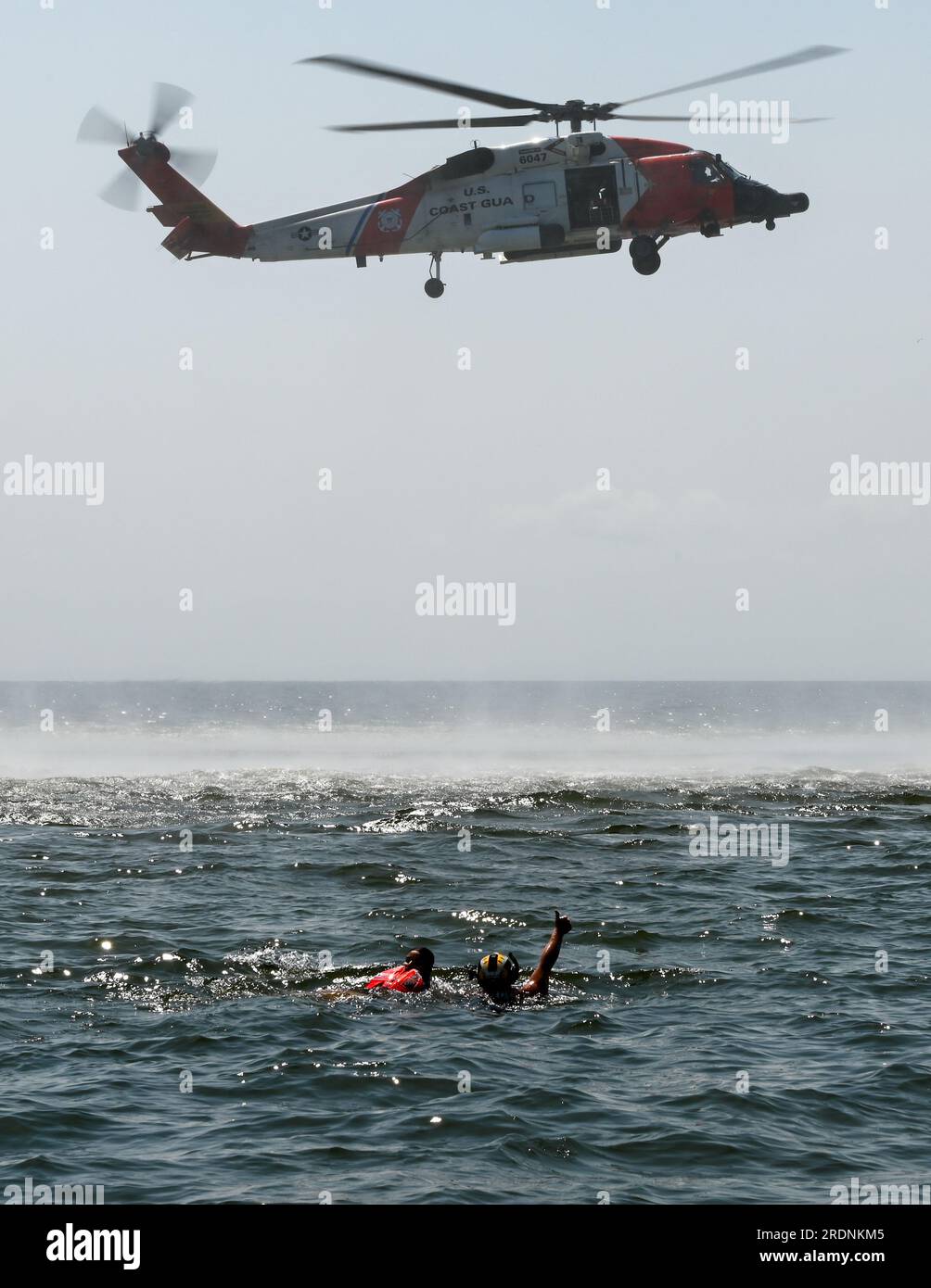 Coast Guard Petty Officer di seconda classe Keegan o'Leary, un tecnico di sopravvivenza dell'aviazione con la stazione della Guardia Costiera di New Orleans, segnala un MH-60 Jayhawk vicino a Gulfport, Mississippi, 19 luglio 2023. Alcuni avieri del 183rd Aeromedical Evacuation Squadron della Mississippi Air National Guard furono sollevati dall'acqua su un elicottero Jayhawk e si ritirarono. (STATI UNITI Foto della Guardia Costiera del sottufficiale di terza classe Ryan Graves) Foto Stock