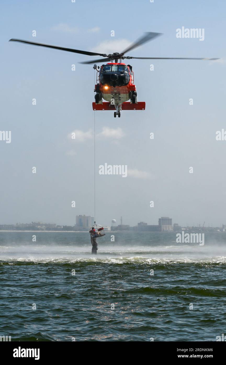 Coast Guard Petty Officer di seconda classe Keegan o'Leary, un tecnico di sopravvivenza dell'aviazione con la stazione della Guardia Costiera di New Orleans, è appeso a un cesto di salvataggio di un MH-60 Jayhawk vicino a Gulfport, Mississippi, 19 luglio 2023. Alcuni avieri del 183rd Aeromedical Evacuation Squadron della Mississippi Air National Guard furono sollevati dall'acqua su un elicottero Jayhawk e si ritirarono. (STATI UNITI Foto della Guardia Costiera del sottufficiale di terza classe Ryan Graves) Foto Stock