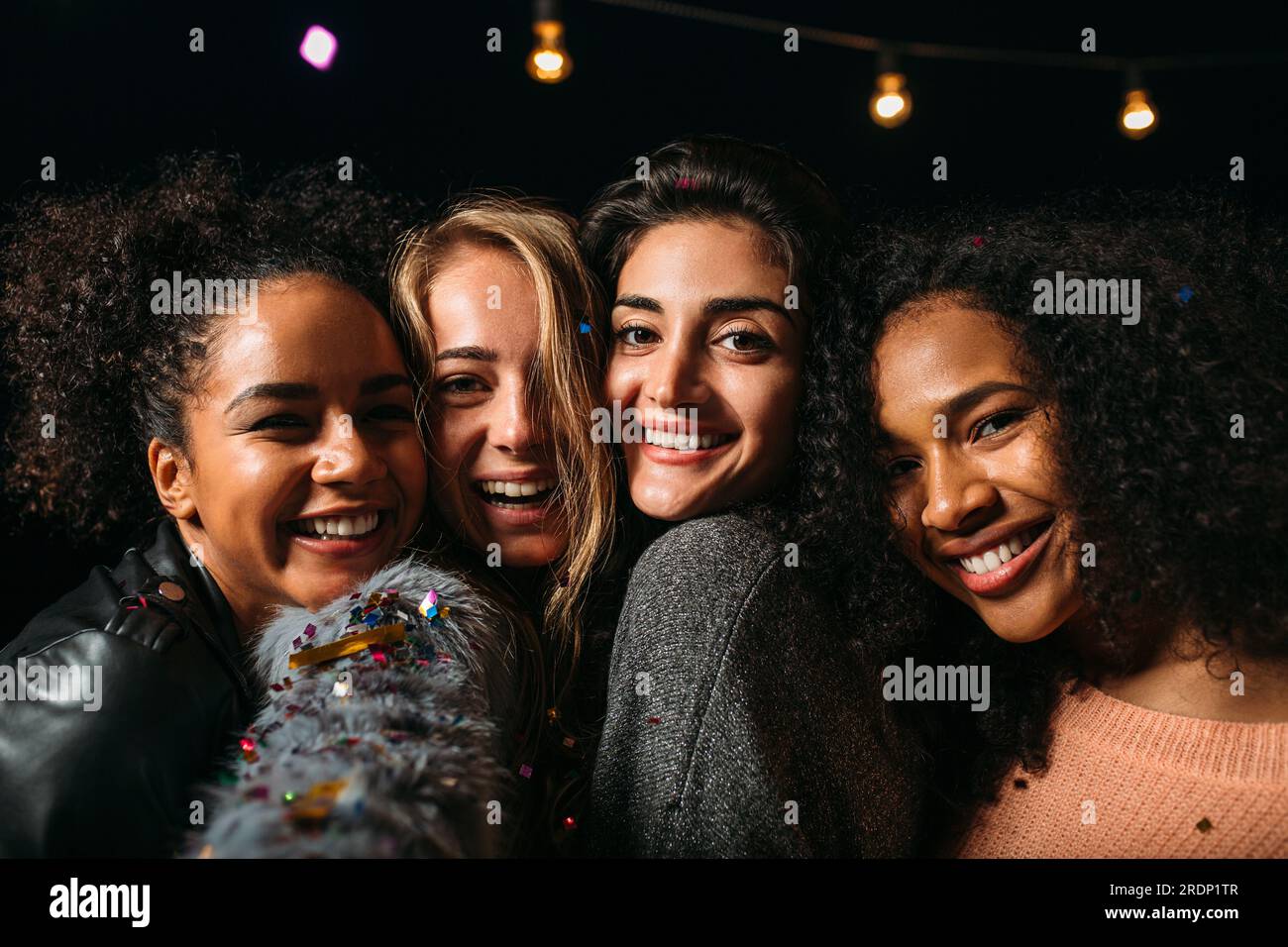 Ritratto di un gruppo di donne diverse che sorridono e guardano la fotocamera di notte Foto Stock