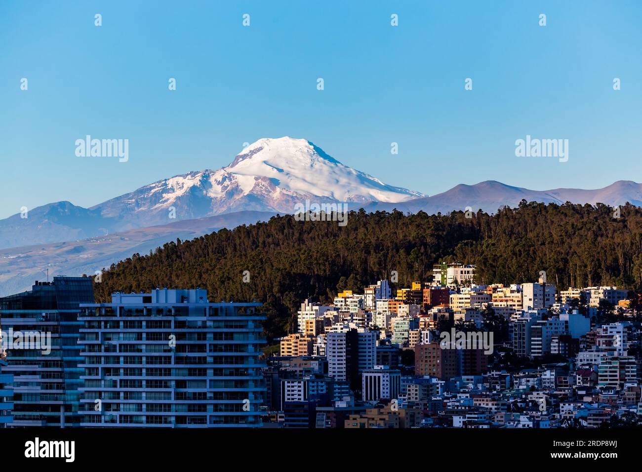 Edifici nella zona settentrionale della città di Quito con il vulcano Cayambe sullo sfondo Foto Stock