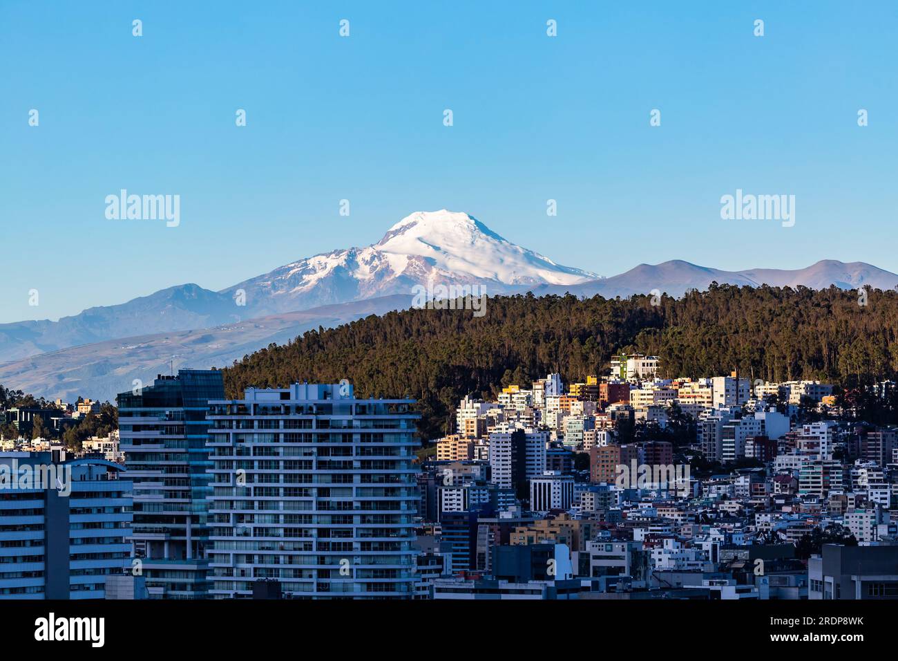 Edifici nella zona settentrionale della città di Quito con il vulcano Cayambe sullo sfondo Foto Stock