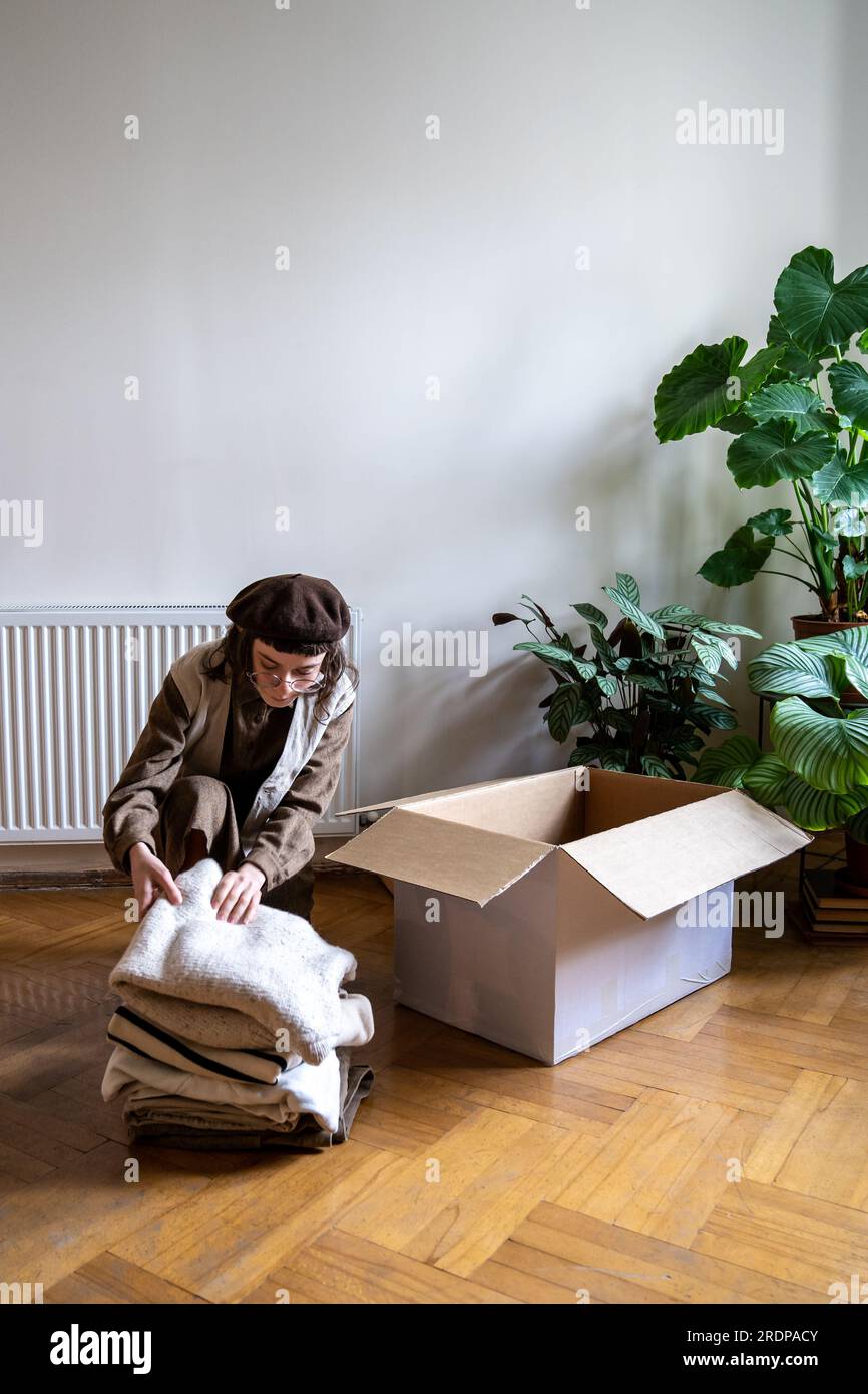 Girl eco-attivista confeziona oggetti da riciclare nella scatola. Consumo consapevole, vestirsi in modo da salvaguardare l'ambiente. Foto Stock
