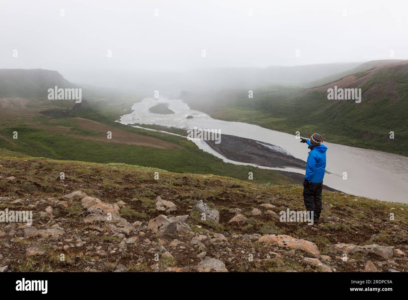 Escursioni in Islanda, concetto di avventura. Viaggiatore singolo maschio in piedi sulla collina vicino ad Asbyrgi e che punta con il dito verso la montagna. Bella Foto Stock