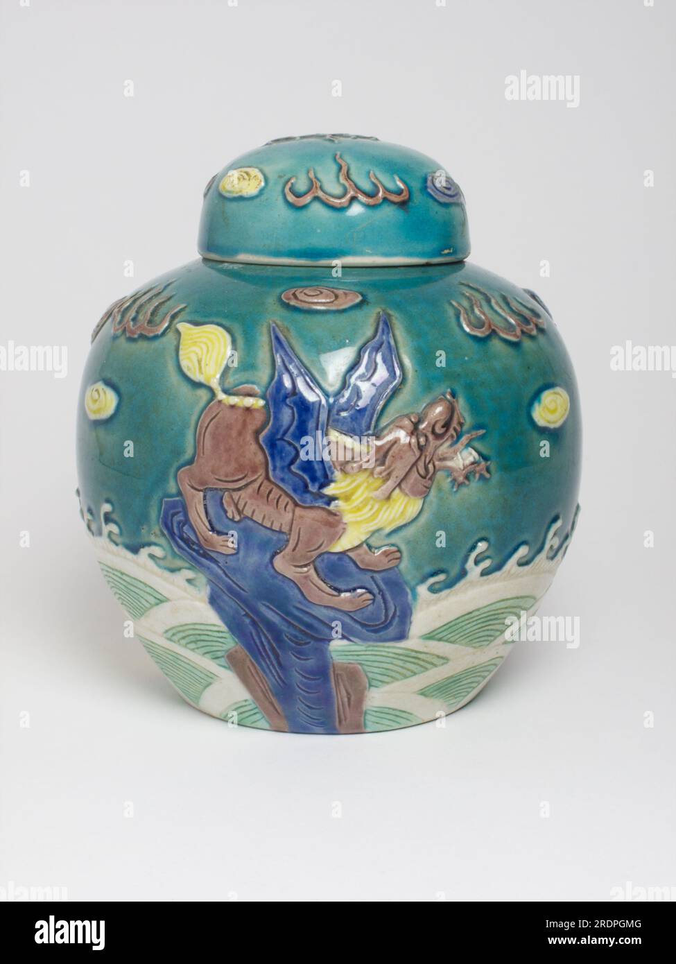 Antico vaso cinese e coperchio decorato in rilievo con tre bestie mitiche in piedi su rocce sopra le onde, realizzate tra la fine del XIX secolo e l'inizio del XX secolo. Foto Stock