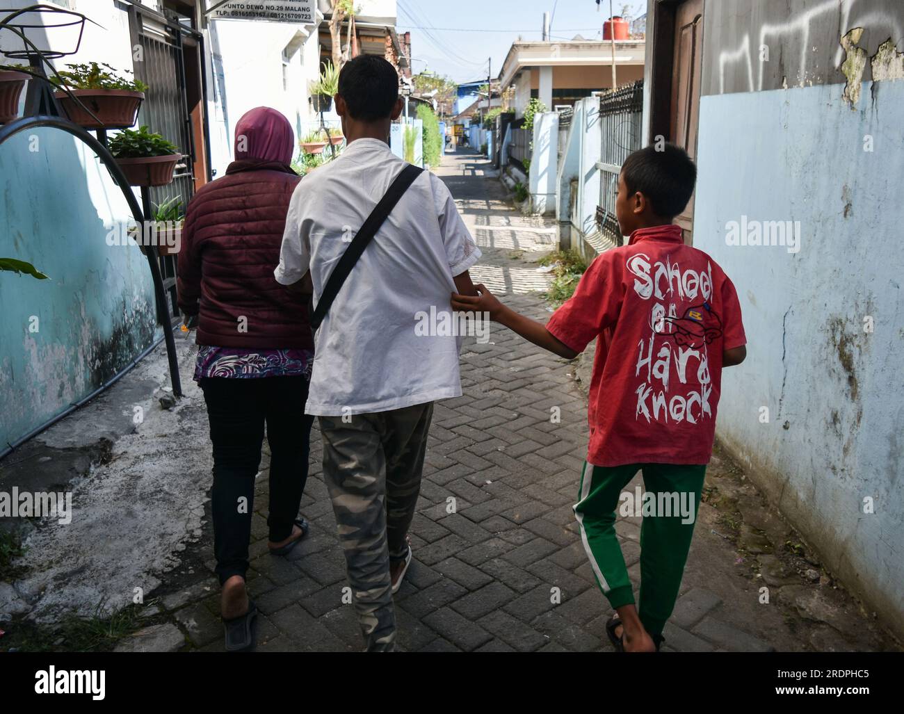 22 luglio 2023, Malang, Giava Orientale, Indonesia: Un paziente con disabilità di cieco (centro) con la sua famiglia torna a casa dal posto di salute locale di disabilità (disabilità Posyandu) nell'ufficio del villaggio di Polehan, Malang City, Giava Orientale, Indonesia il 22 luglio 2023. La disabilità Posyandu fornisce controlli sanitari di base (obesità, zucchero nel sangue, colesterolo e nutrizione), controlli motori, servizi psicologici e riflessologia della disabilità. Il numero di pazienti con disabilità è di 80 persone con disabilità mentali, disabilità fisiche, ciechi, sordi e disabili.Posyandu disabilità è un servizio sanitario gratuito Foto Stock