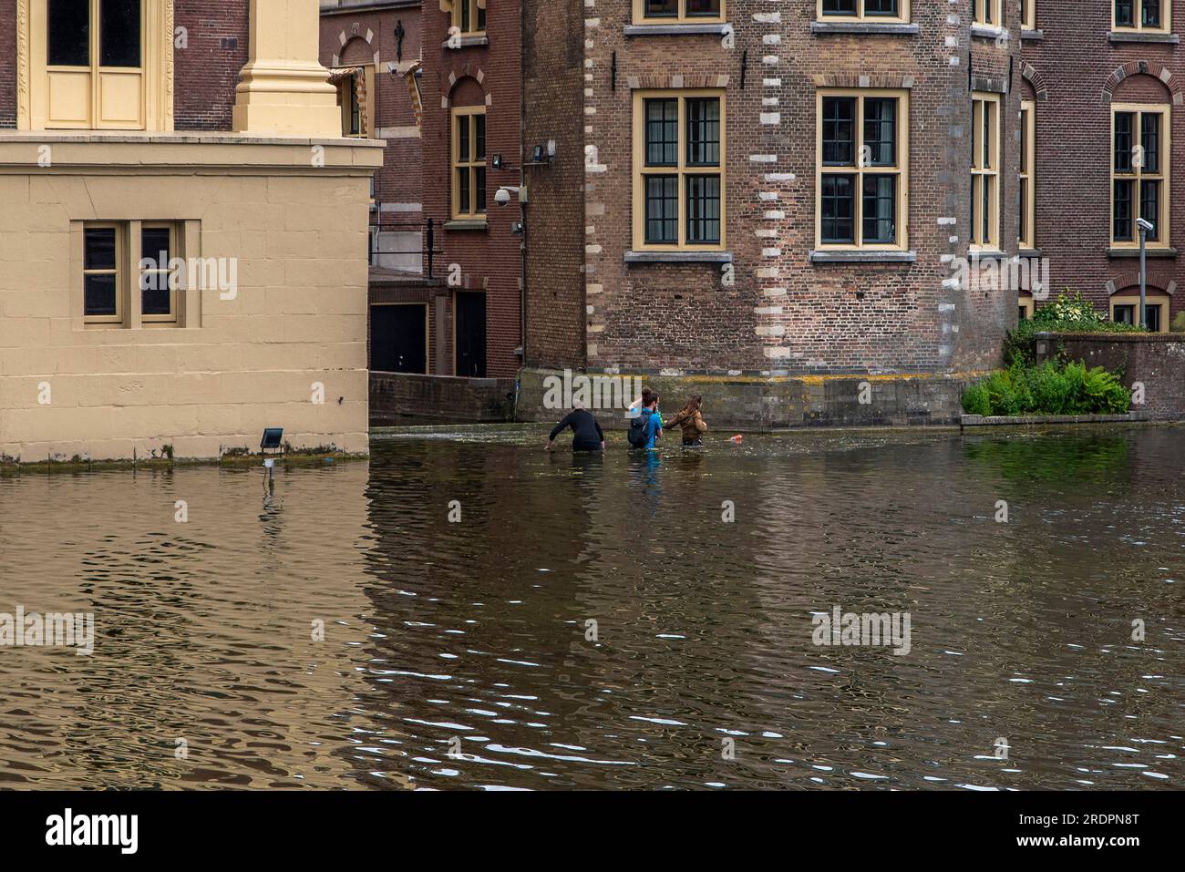 Den Haag, Olanda meridionale, Paesi Bassi. 22 luglio 2023. Tre attivisti per il clima camminano attraverso l'acqua dell'Hofvijfer per raggiungere dove manifesteranno di fronte agli uffici del governo olandese. Gli attivisti del clima con Extinction Rebellion hanno dimostrato esattamente alle 18:00 (UTC 2) lo spostamento dell'"Orologio climatico" da sei anni a cinque. Questa dimostrazione è stata una delle 26 che si sono svolte in tutto il mondo. (Immagine di credito: © James Petermeier/ZUMA Press Wire) SOLO USO EDITORIALE! Non per USO commerciale! Foto Stock