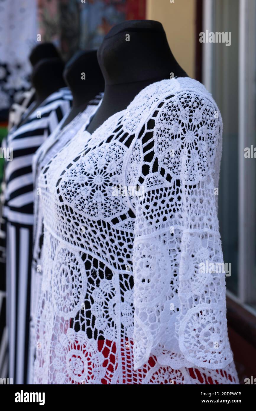 Top in pizzo decorati in bianco su bambole nere di moda di fronte alla vetrina di un negozio Foto Stock