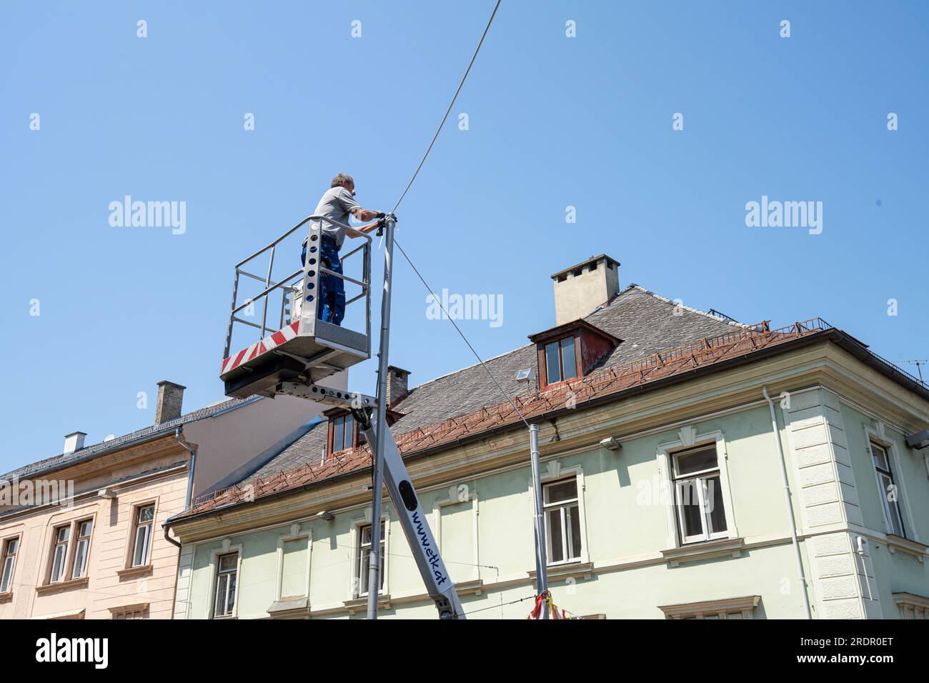 Villach, Austria. 18 luglio 2023. un tecnico si è sollevato su un cestino mentre lavorava su cavi elettrici in una strada del centro città Foto Stock