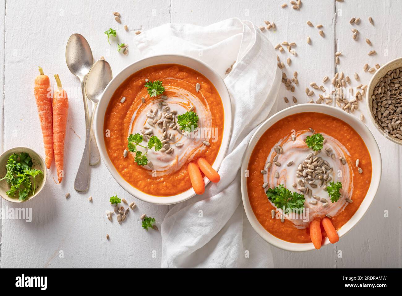 Gustosa zuppa di carote come piatto di stagione. Zuppa di carote con erbe e semi in un recipiente bianco. Foto Stock