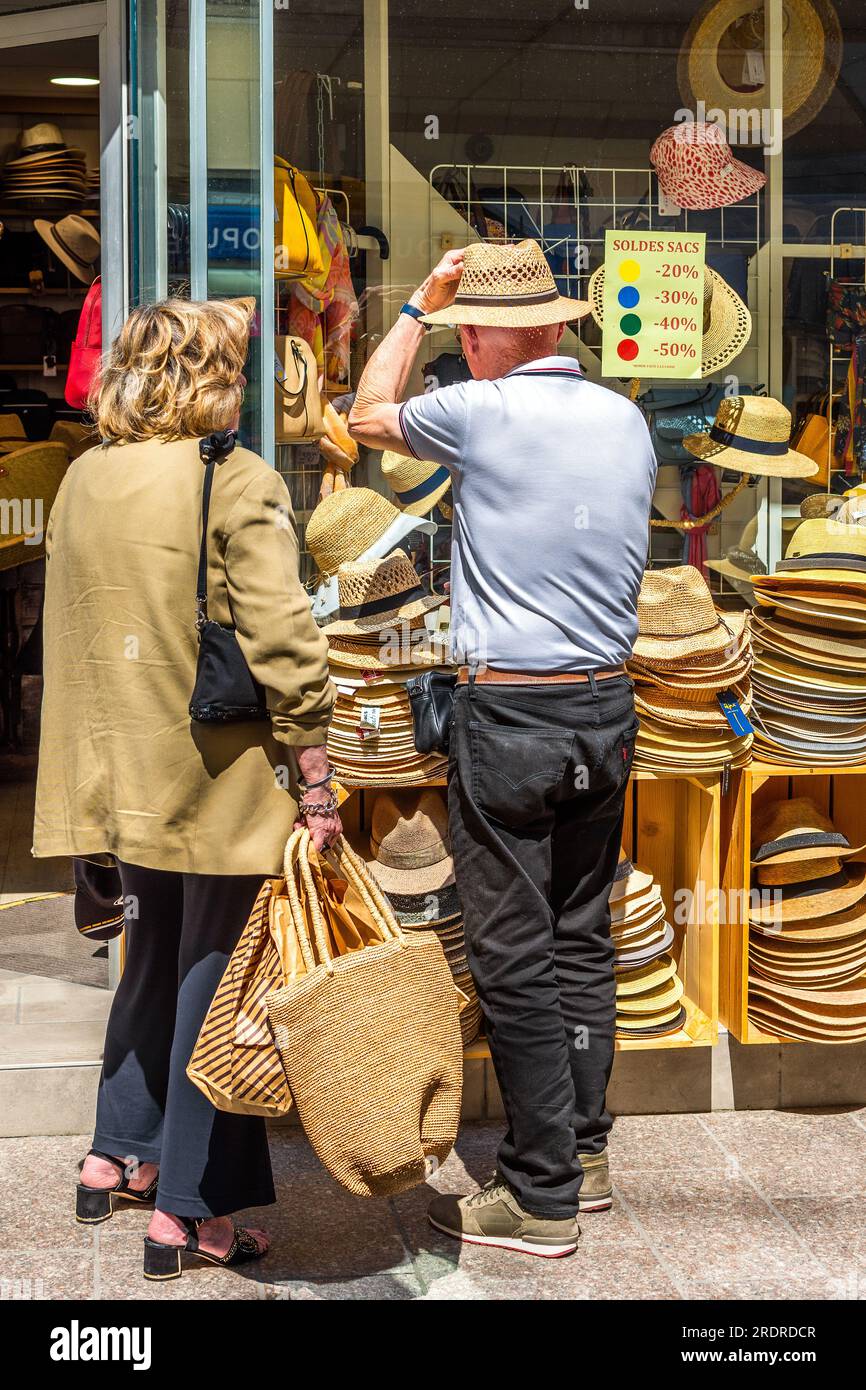 Uomo che prova i cappelli di paglia fuori dal centro della città - Loches, Indre-et-Loire (37), Francia. Foto Stock