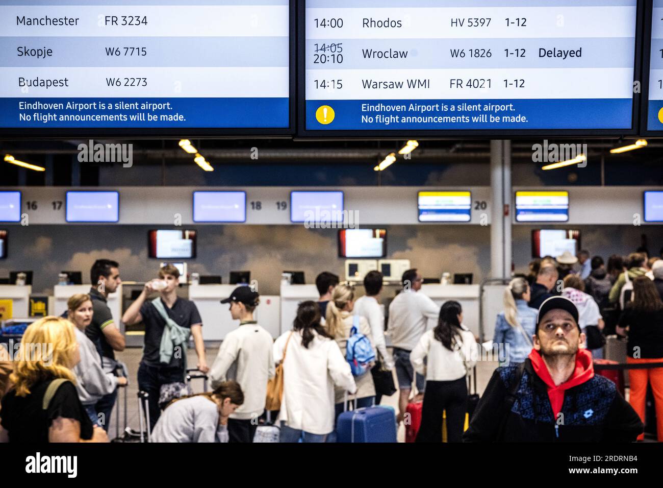 EINDHOVEN - i viaggiatori si trovano al banco del check-in mentre un volo Transavia per Rodi viene annunciato sulla schermata delle partenze. Transavia continuerà a volare verso l'isola greca per il momento. La compagnia aerea, tuttavia, si tiene in contatto con le autorità per monitorare la sicurezza. Gli incendi infuriano nel sud di Rodi. ANP ROB ENGELAAR netherlands Out - belgium Out Foto Stock