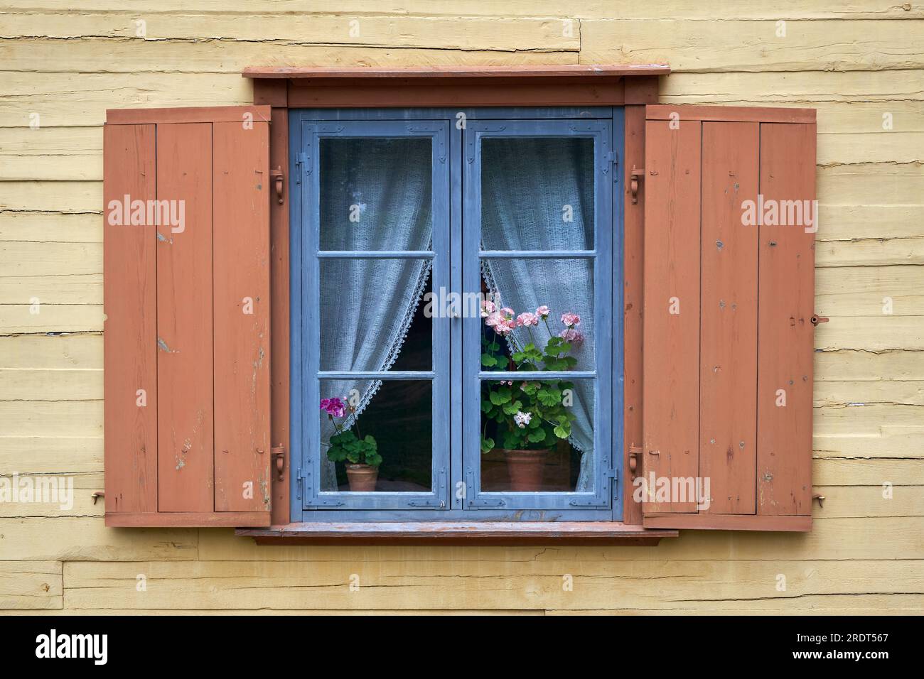 Finestra rustica d'epoca con fiori di geranio sul davanzale interno. Foto Stock