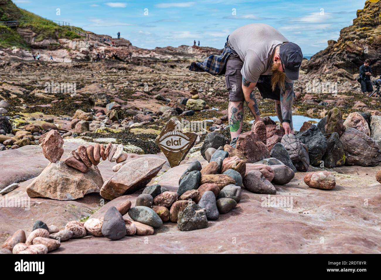 Arron Tierney Balancing Stones on Beach, European Stone Stacking Championship and Land Art Festival, Dunbar, East Lothian, Scozia, Regno Unito Foto Stock