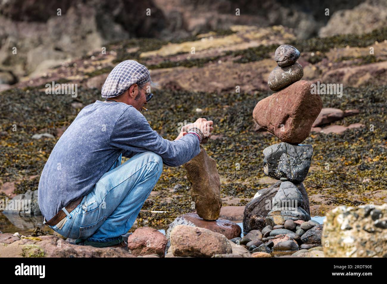 Charlie Jordan bilanciando pietre sulla spiaggia, European Stone Stacking Championship e Land Art Festival, Dunbar, East Lothian, Scozia, Regno Unito Foto Stock