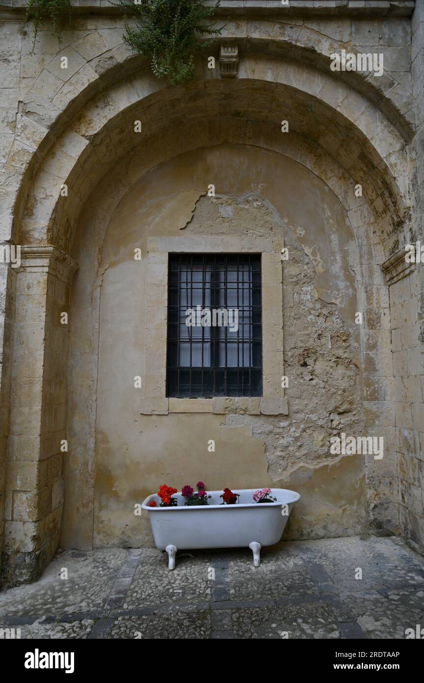 Vasca da bagno in porcellana bianca d'epoca utilizzata come letto di fiori nel cortile di Palazzo Landolina a noto in Sicilia. Foto Stock