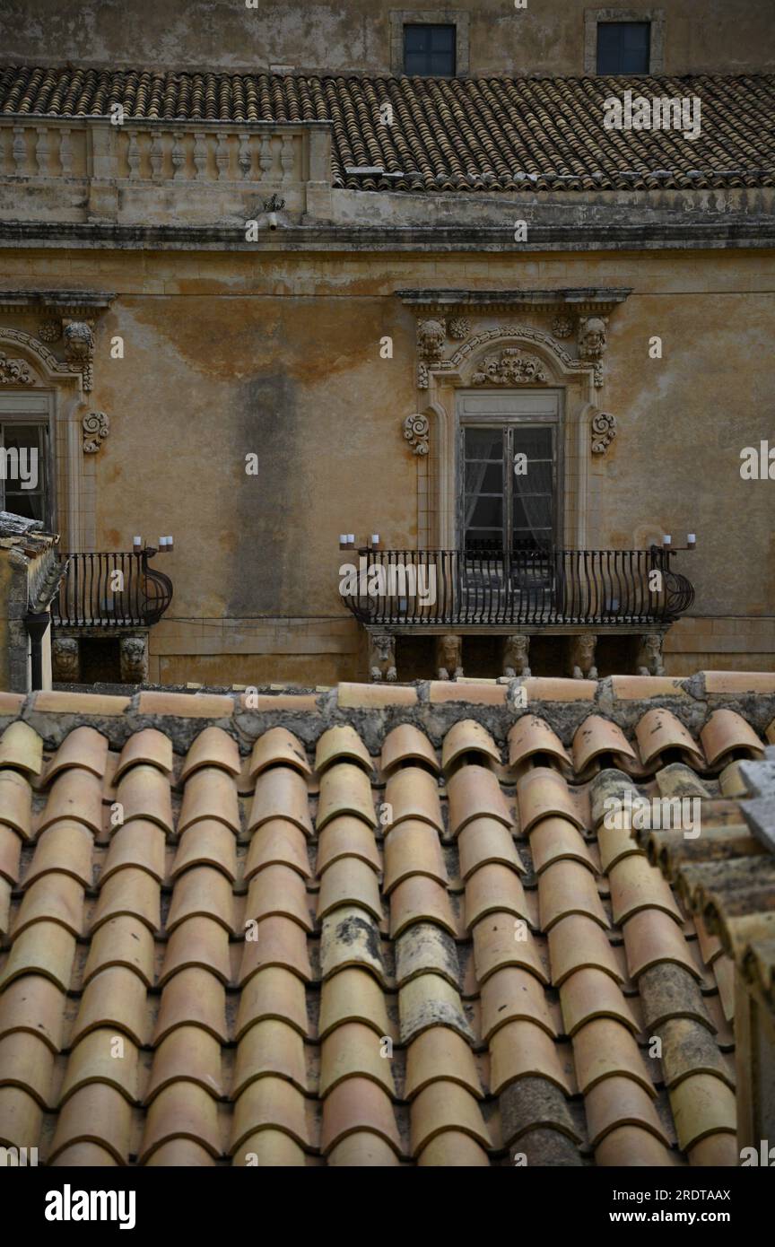 Paesaggio urbano con vista panoramica di Palazzo Landolina, come visto su antichi tetti di tegole di argilla a noto in Sicilia, Italia. Foto Stock