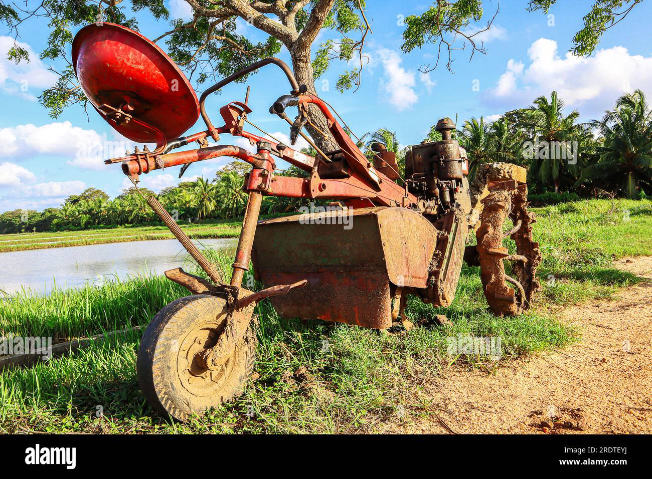 Vecchio trattore arrugginito sul campo con sfondo blu cielo. Foto Stock