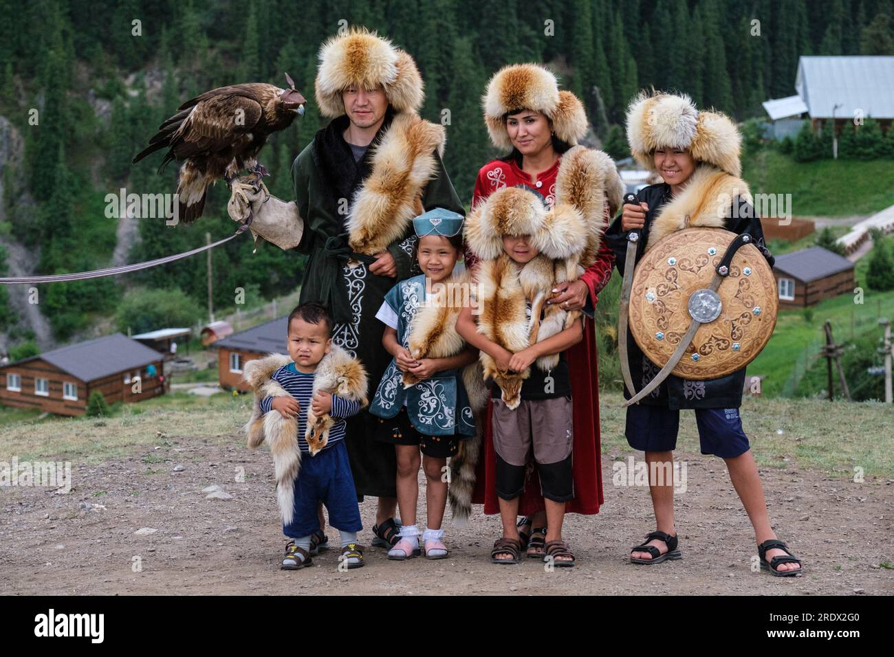 Kazakistan, Parco Nazionale dei Laghi di Kolsay. Famiglia in posa per una foto in costume tradizionale con falco con cappuccio. Foto Stock