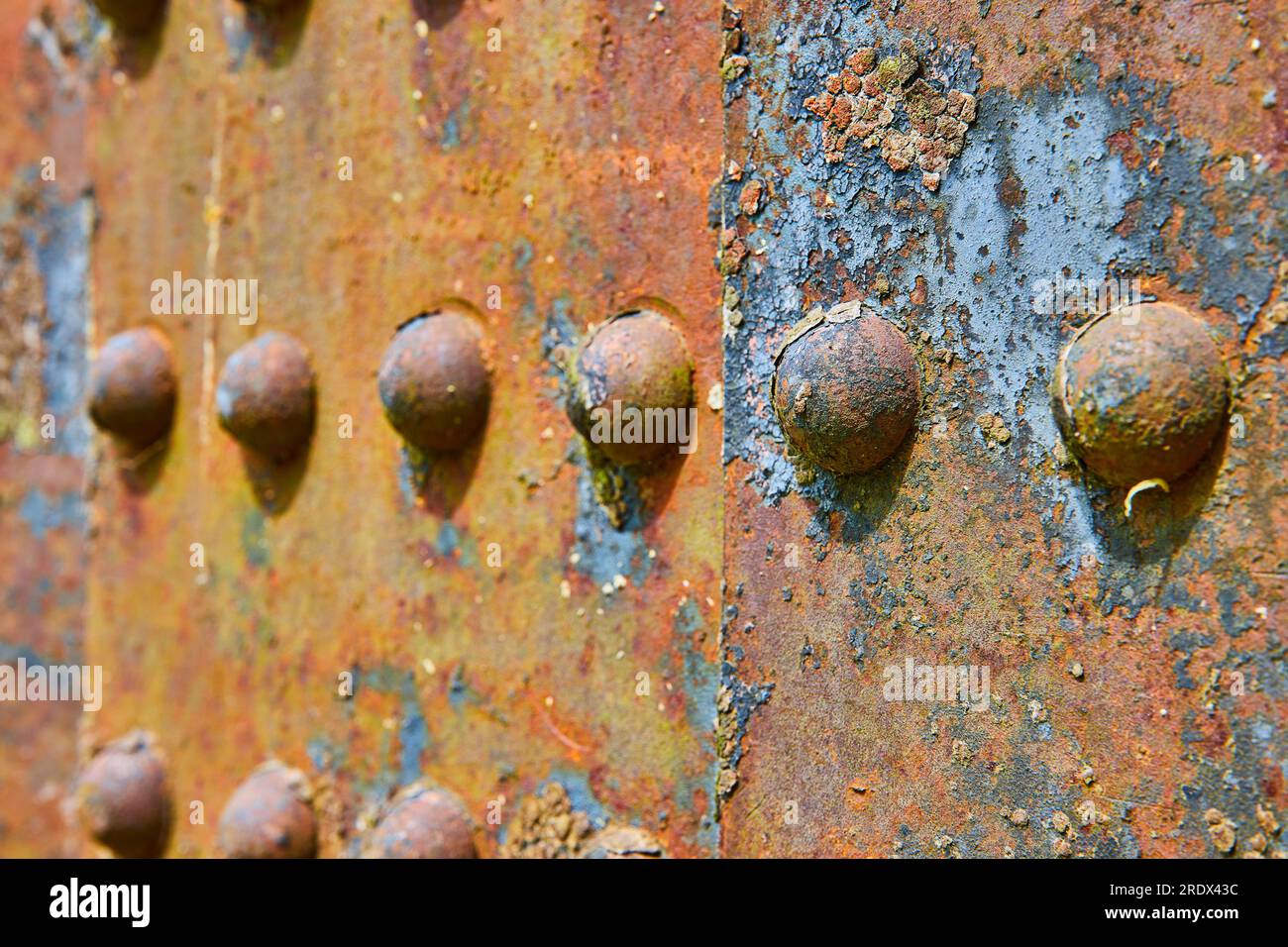 Corrosione industriale delle pareti metalliche in ferro arrugginito dei rivetti con fondo in scaglie blu e gialle asset  Foto Stock