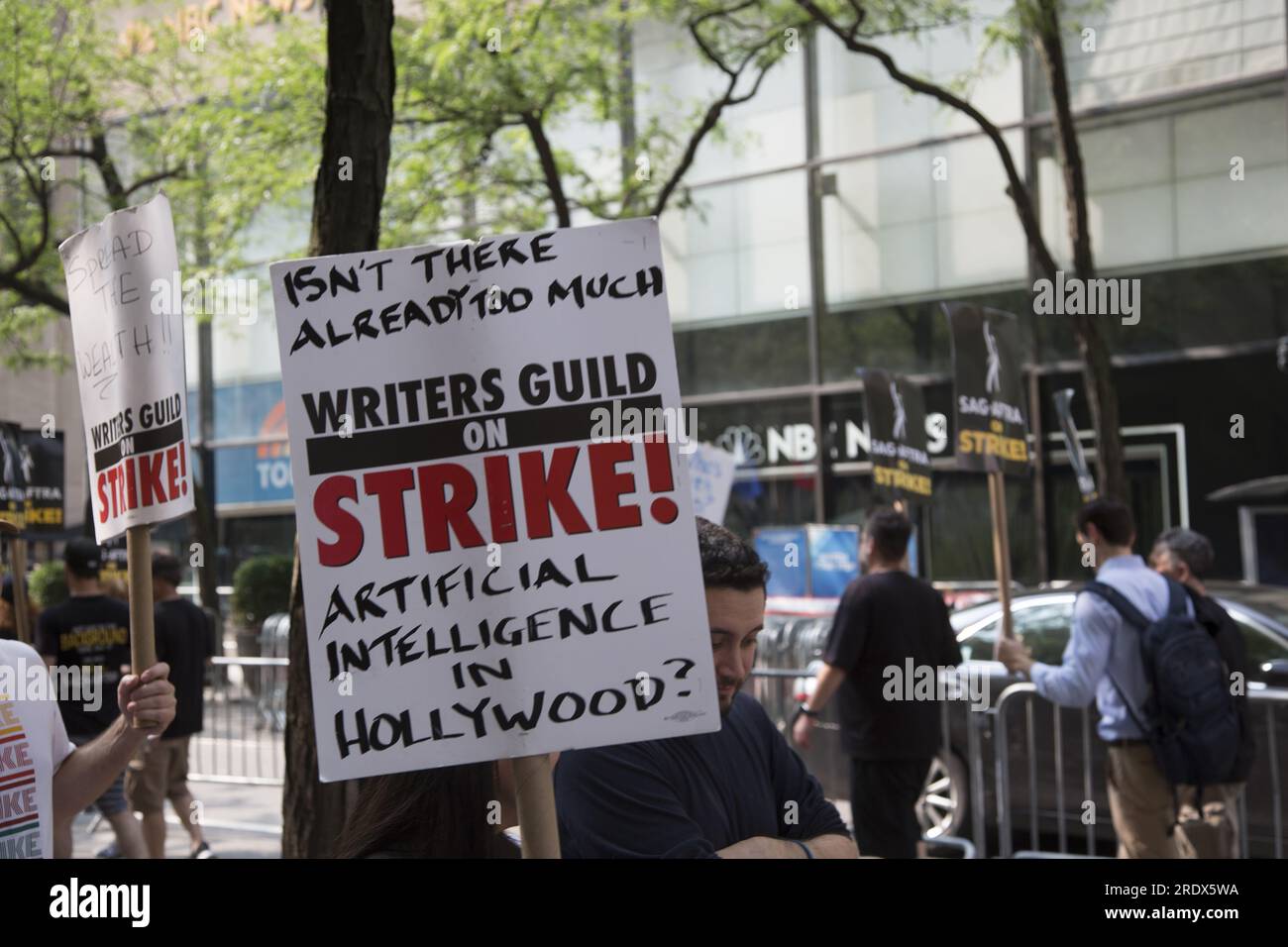 New York City: Lo sciopero continua tra gli Writers Guild of America insieme ai membri del sindacato SAG-AFTRA con linee di picchetto in più località a Manhattan. Gli scioperanti si esibiscono all'esterno degli NBC Studios sulla W. 49th Street del Rockefeller Center, paralizzando l'industria dello spettacolo. Foto Stock