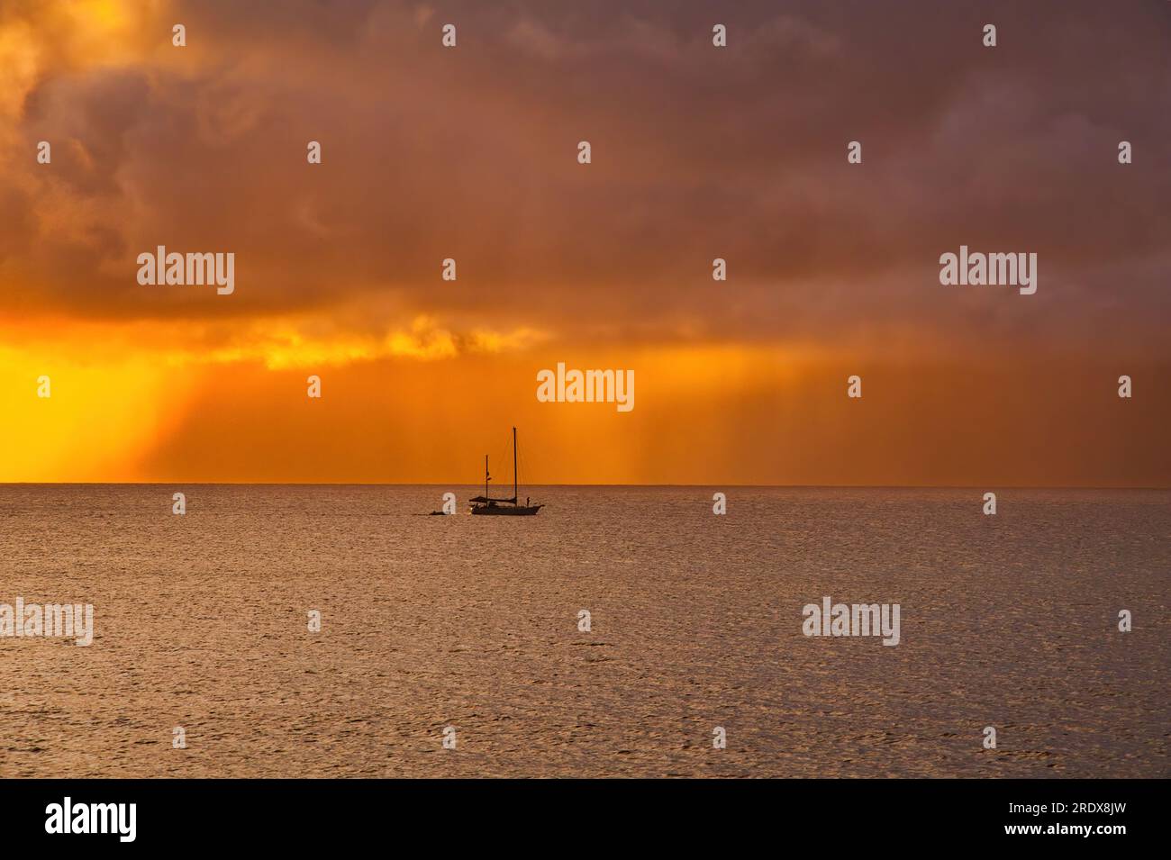 Barca a vela solitaria al tramonto con pioggia che cade in lontananza. Foto Stock