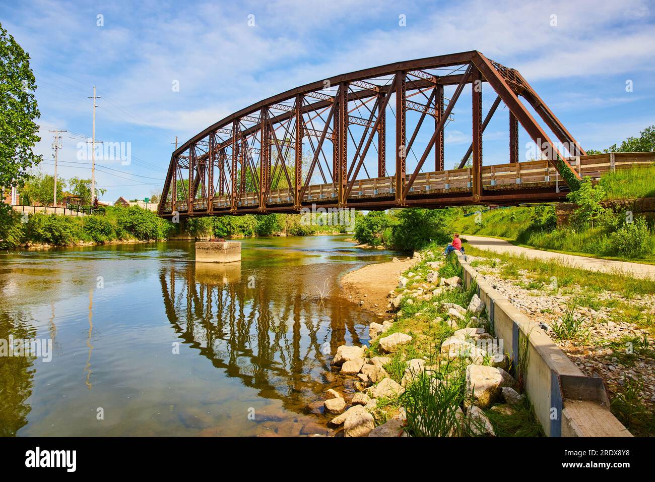 Estate con il fiume Kokosing in Ohio con una persona seduta e un vecchio ponte ferroviario Foto Stock