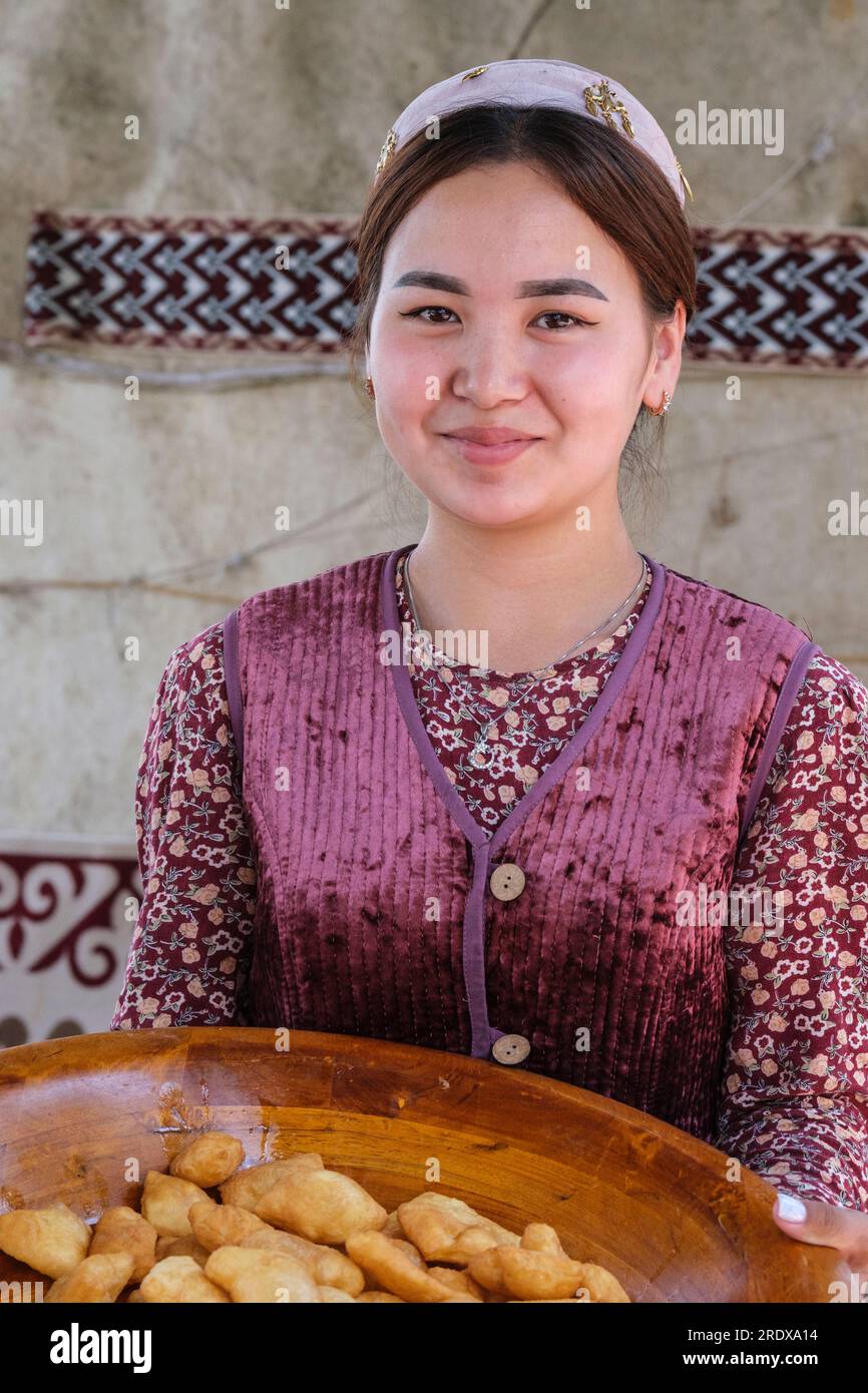 Kazakistan, Huns Ethno Village. Giovane donna kazaka che offre pasticceria Baursak. Foto Stock