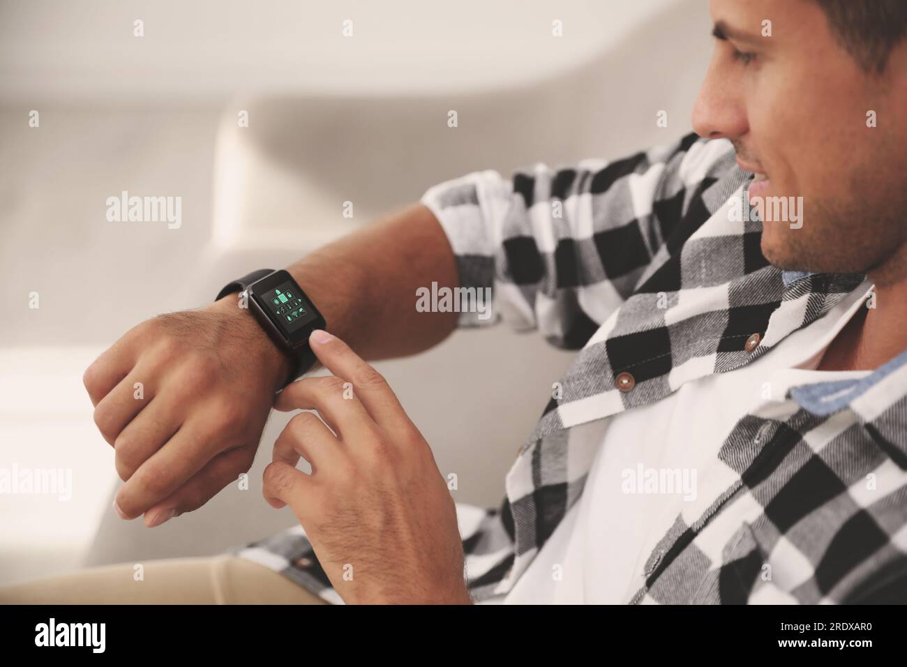 Sistema di controllo Smart Home da uomo tramite smartwatch al chiuso. Interfaccia app con icone sul display Foto Stock