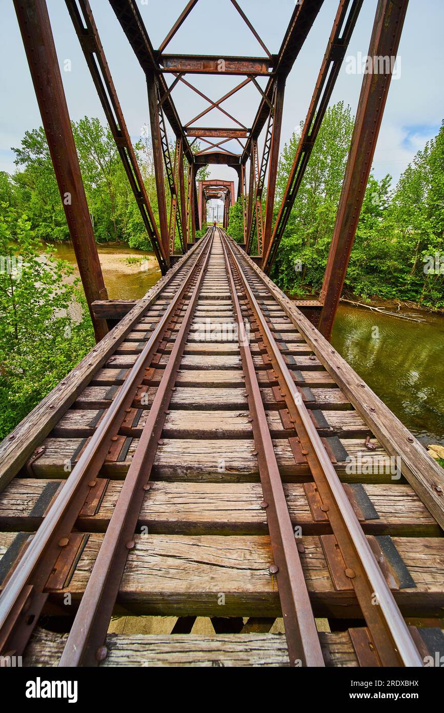 Verticale di binari dettagliati e travi in legno con vista del fiume sottostante e di alberi verdi distanti Foto Stock