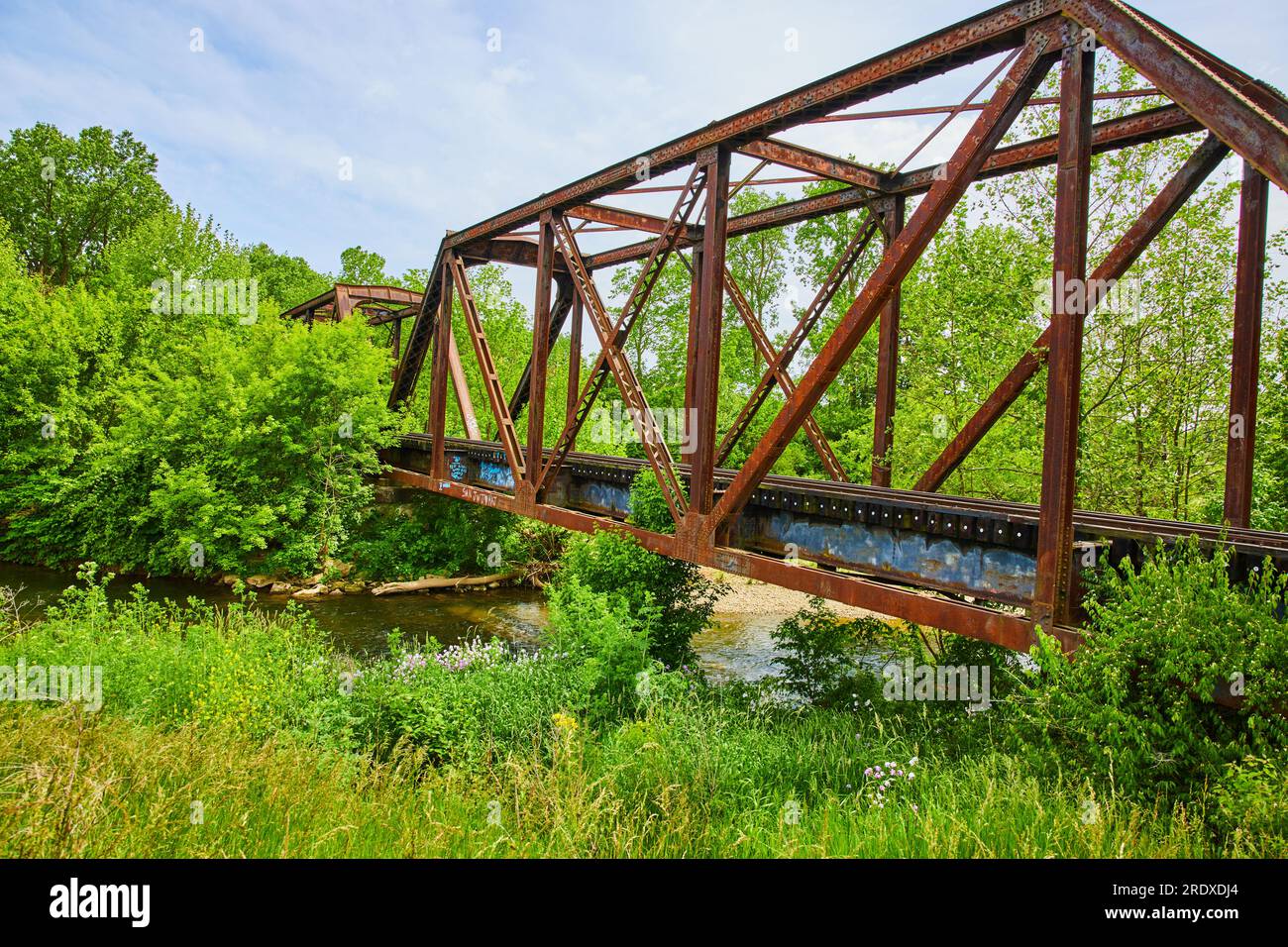 Vecchio ponte ferroviario che attraversa la foresta con il fiume Kokosing Foto Stock