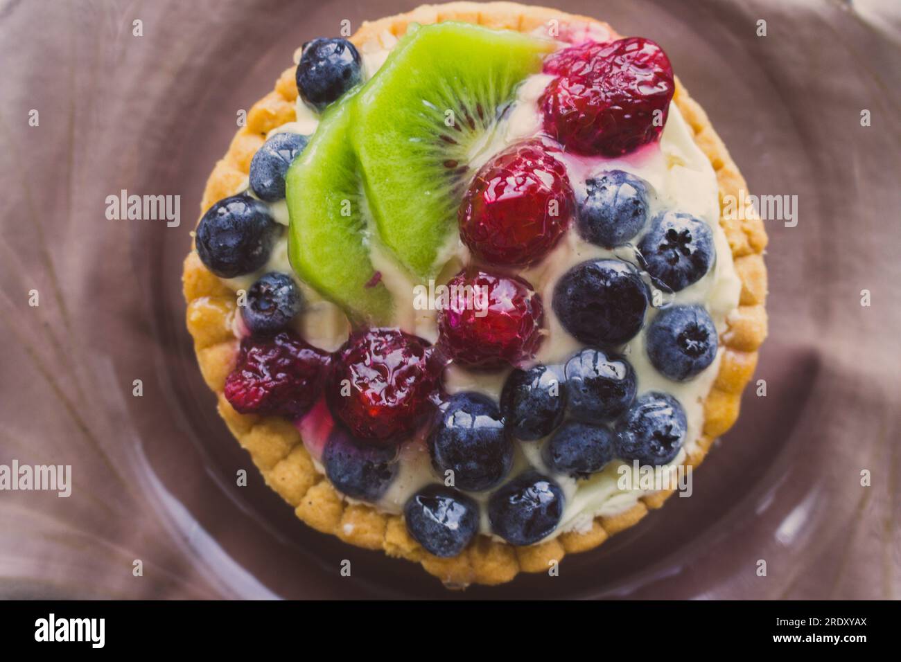 Torta gustosa con frutti di bosco freschi da vicino. Crostata fatta in casa con mirtilli, lamponi e fette di kiwi. Delizioso dessert. Colazione dolce. Foto Stock