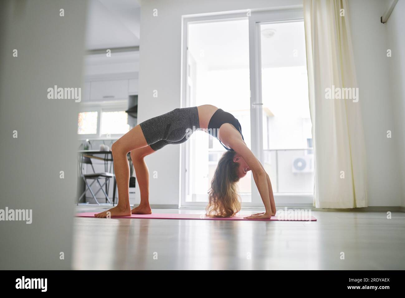 Giovane donna a praticare yoga a casa Foto Stock