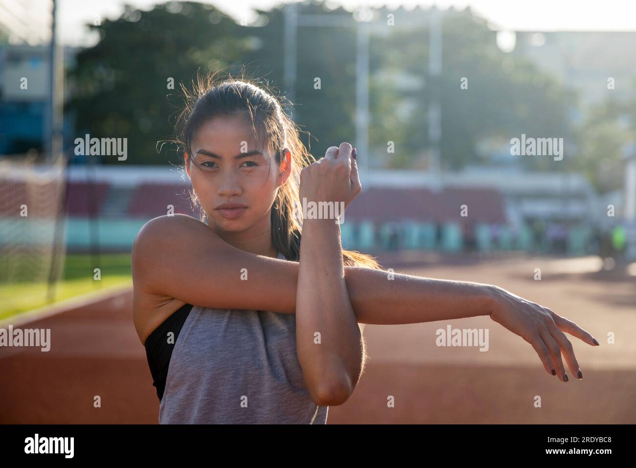 Giovane donna che fa esercizio di stretching in campo sportivo Foto Stock