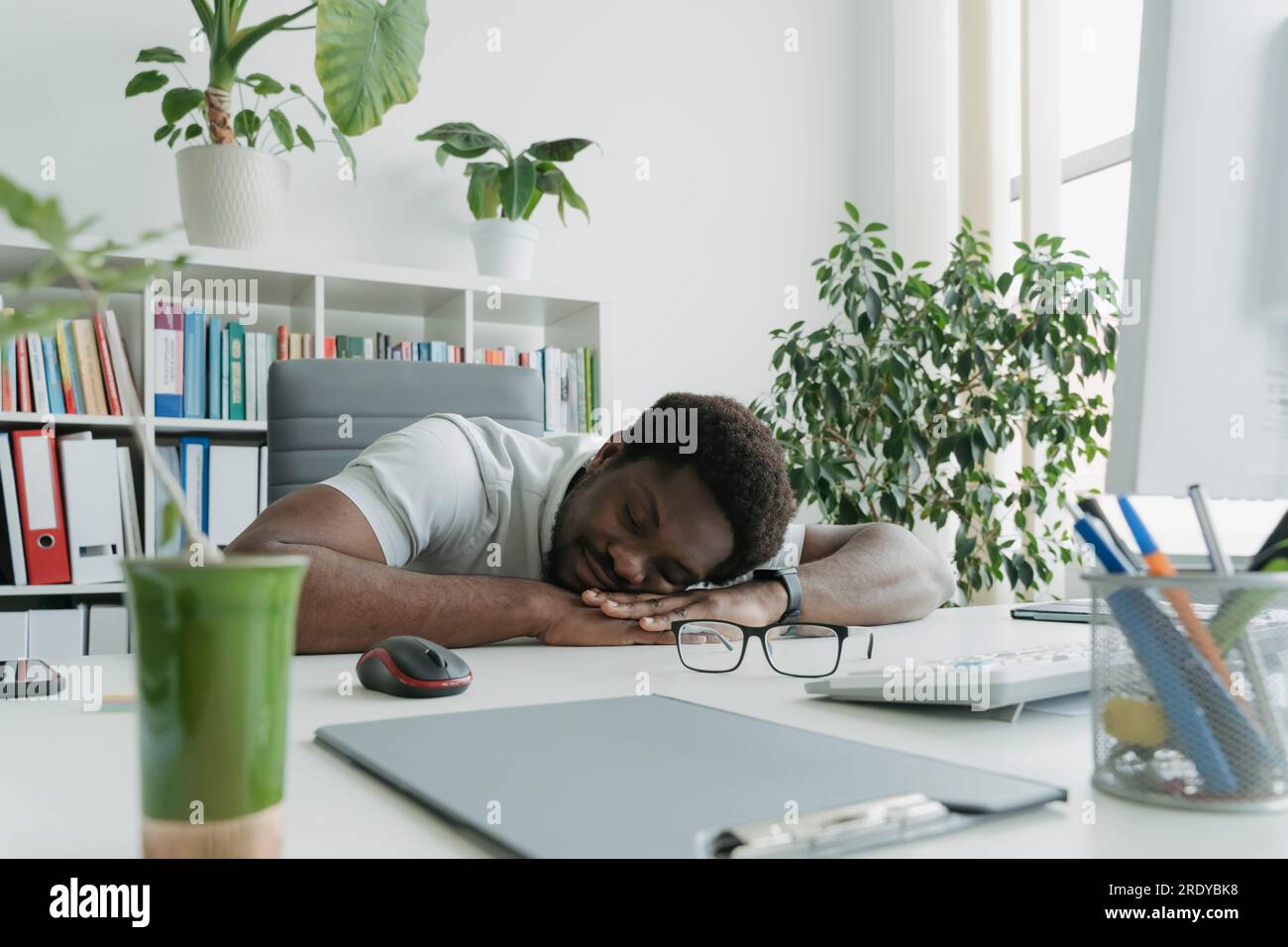 Un giovane uomo d'affari che dorme con la faccia in giù alla scrivania Foto Stock