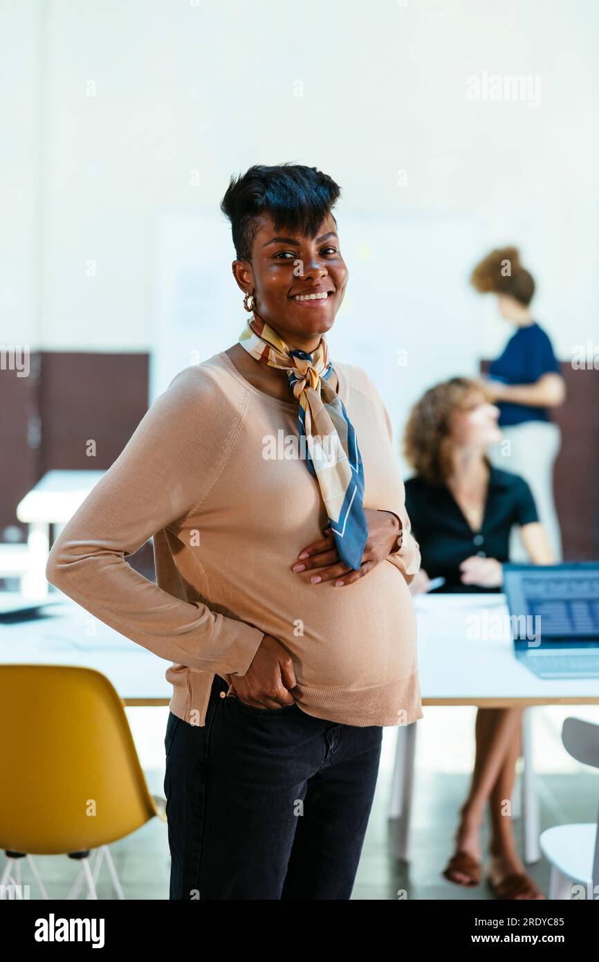 Felice donna d'affari incinta in carica Foto Stock