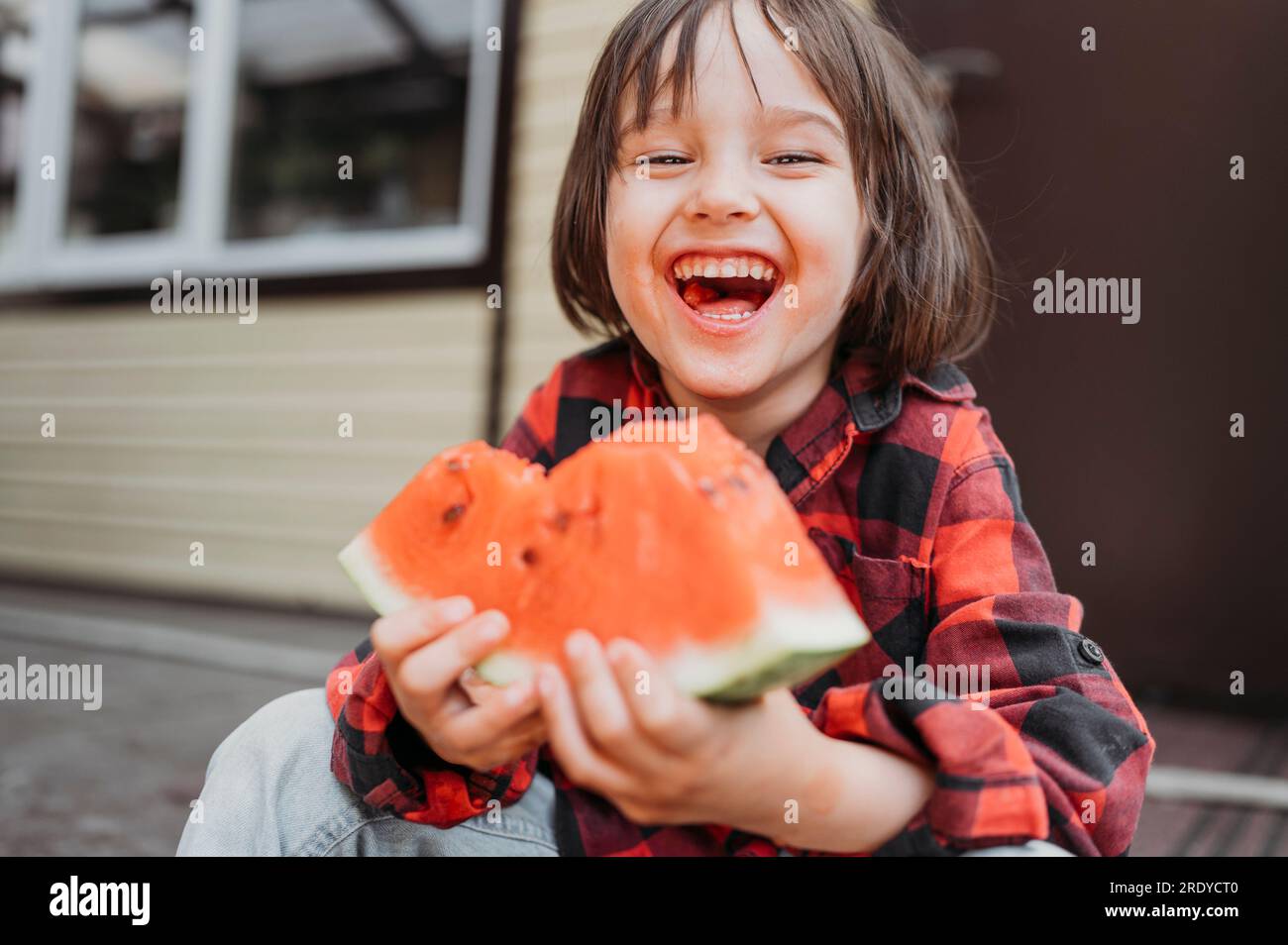 Un ragazzo allegro che tiene una fetta di anguria fresca Foto Stock