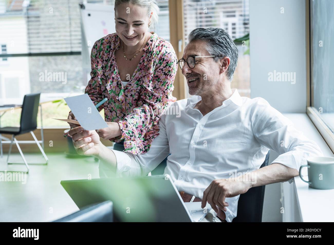 Donna d'affari sorridente e uomo d'affari che guarda la fotografia in ufficio Foto Stock