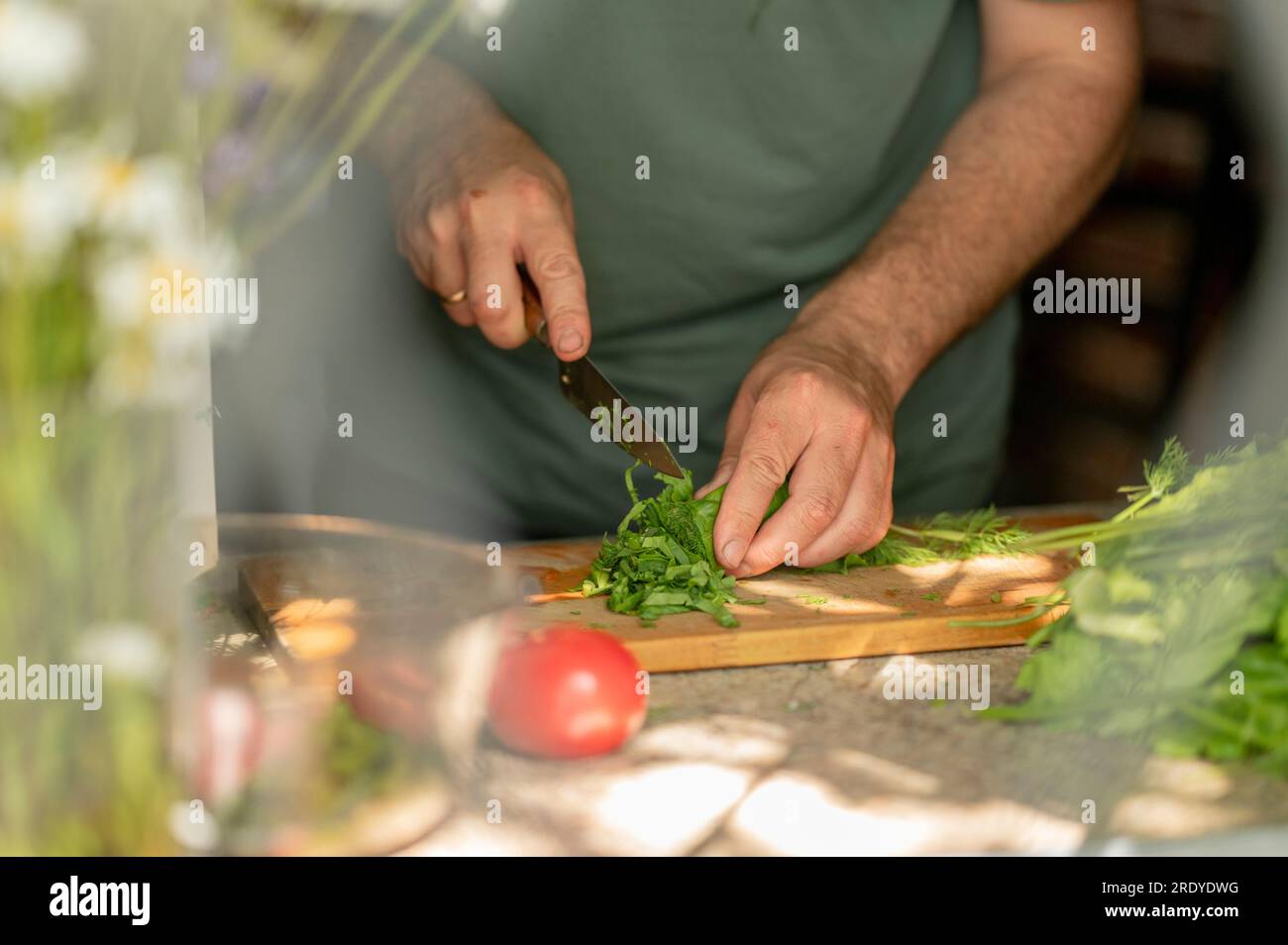 Uomo che trita verdure a foglia verde a casa Foto Stock