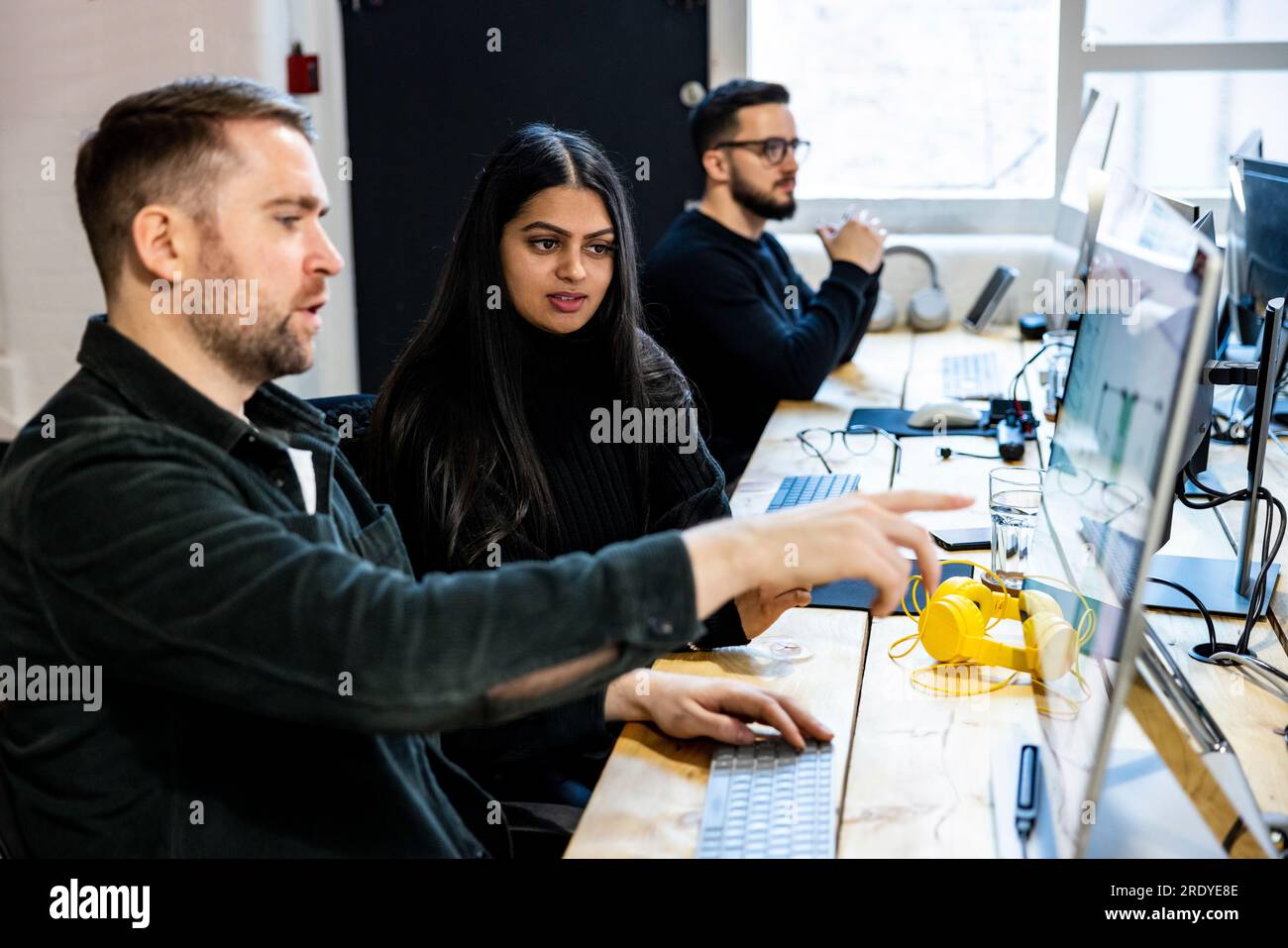 Giovane donna d'affari con un collega che parla al computer Foto Stock