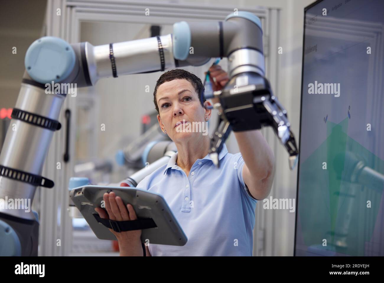Ingegnere che controlla le apparecchiature di supporto del braccio robotizzato nel settore industriale Foto Stock
