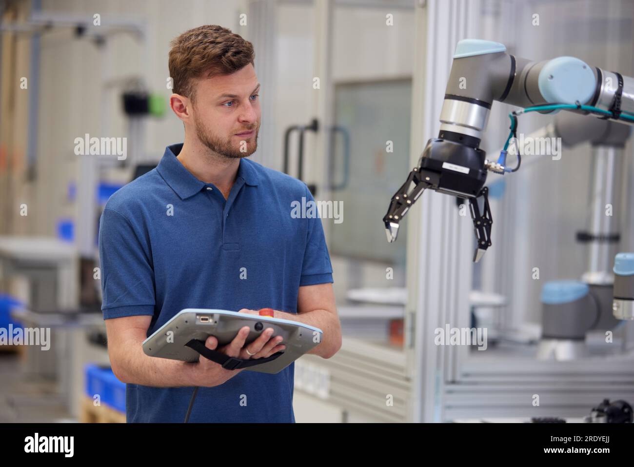 Tecnico che utilizza il braccio robotico utilizzando apparecchiature industriali Foto Stock