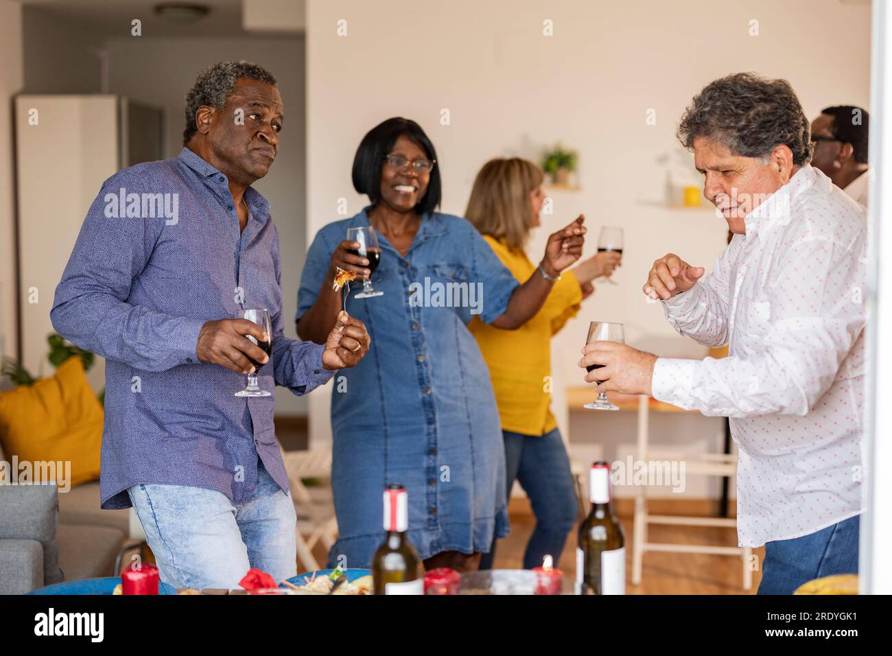 Felici amici anziani multiculturali che ballano insieme a cena Foto Stock