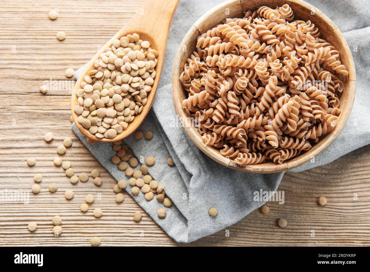 Lenticchie verdi fusilli su un vecchio sfondo di legno. Una ciotola di pasta cruda e lenticchie verdi. Pasta senza glutine. Foto Stock