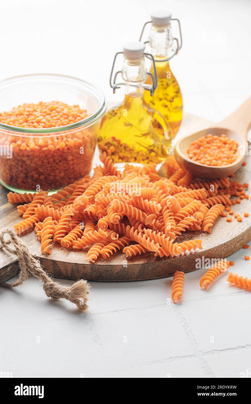 Lenticchie rosse fusilli su fondo grigio in cemento. Ciotola con pasta cruda e lenticchie rosse. Pasta senza glutine. Foto Stock