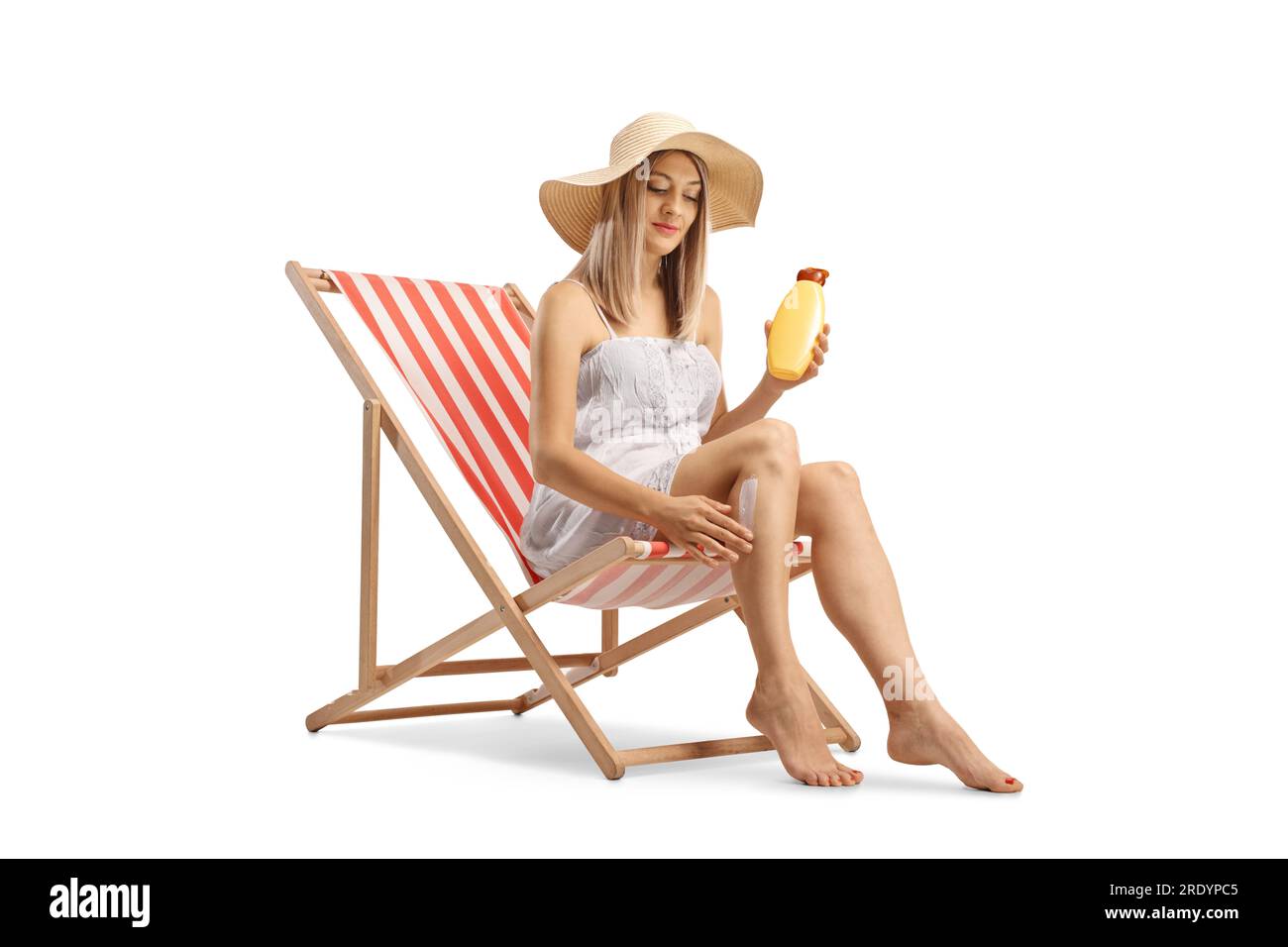 Donna seduta su una sedia a sdraio e che indossa crema solare isolata su sfondo bianco Foto Stock