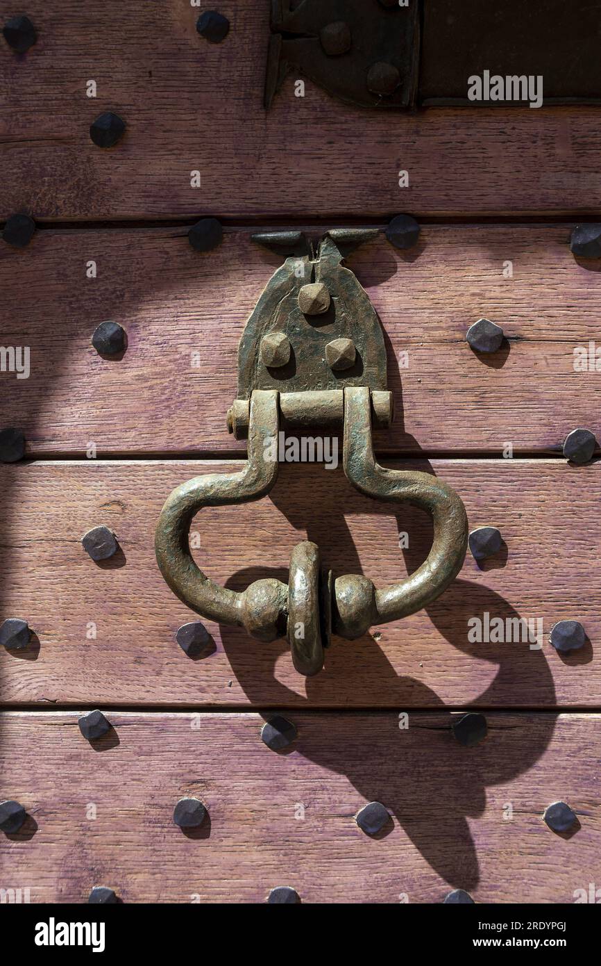 Vista dettagliata di un battitore in ottone su una porta in legno con chiodi decorativi Foto Stock
