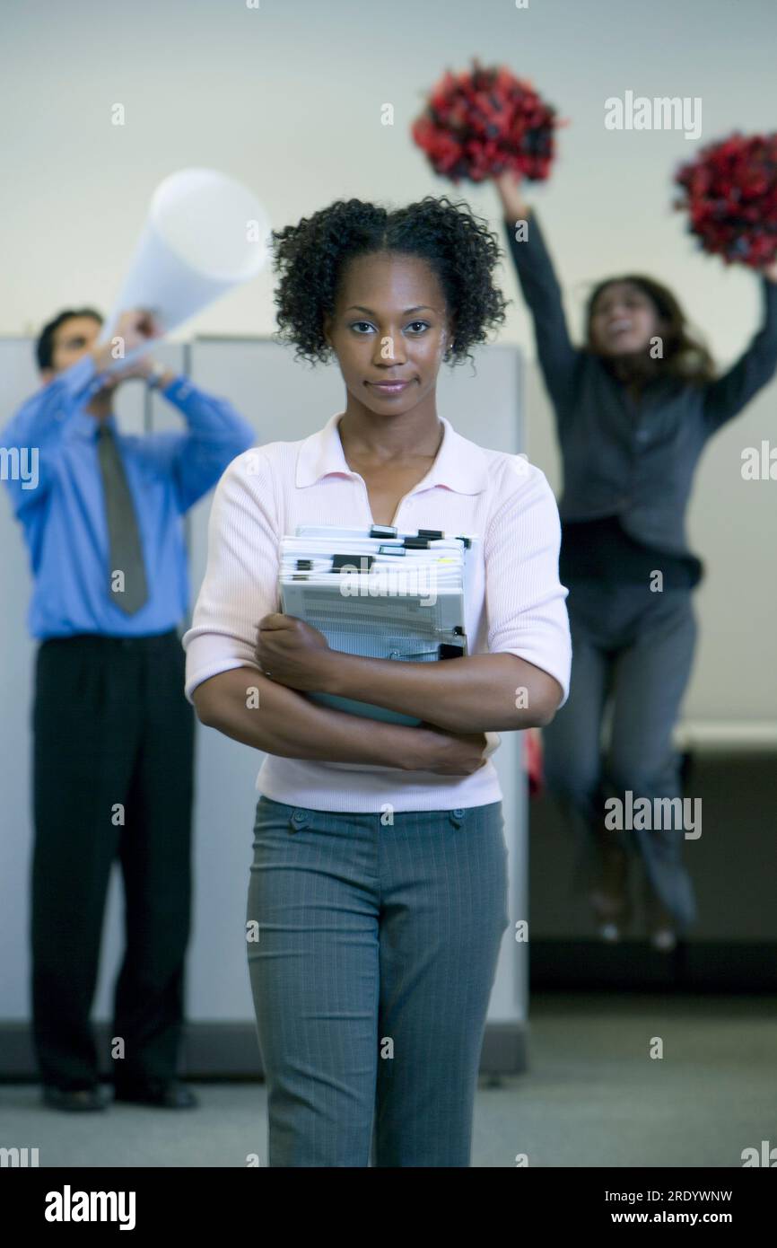 Accolta dai suoi colleghi, una donna sorride al lavoro. Foto Stock