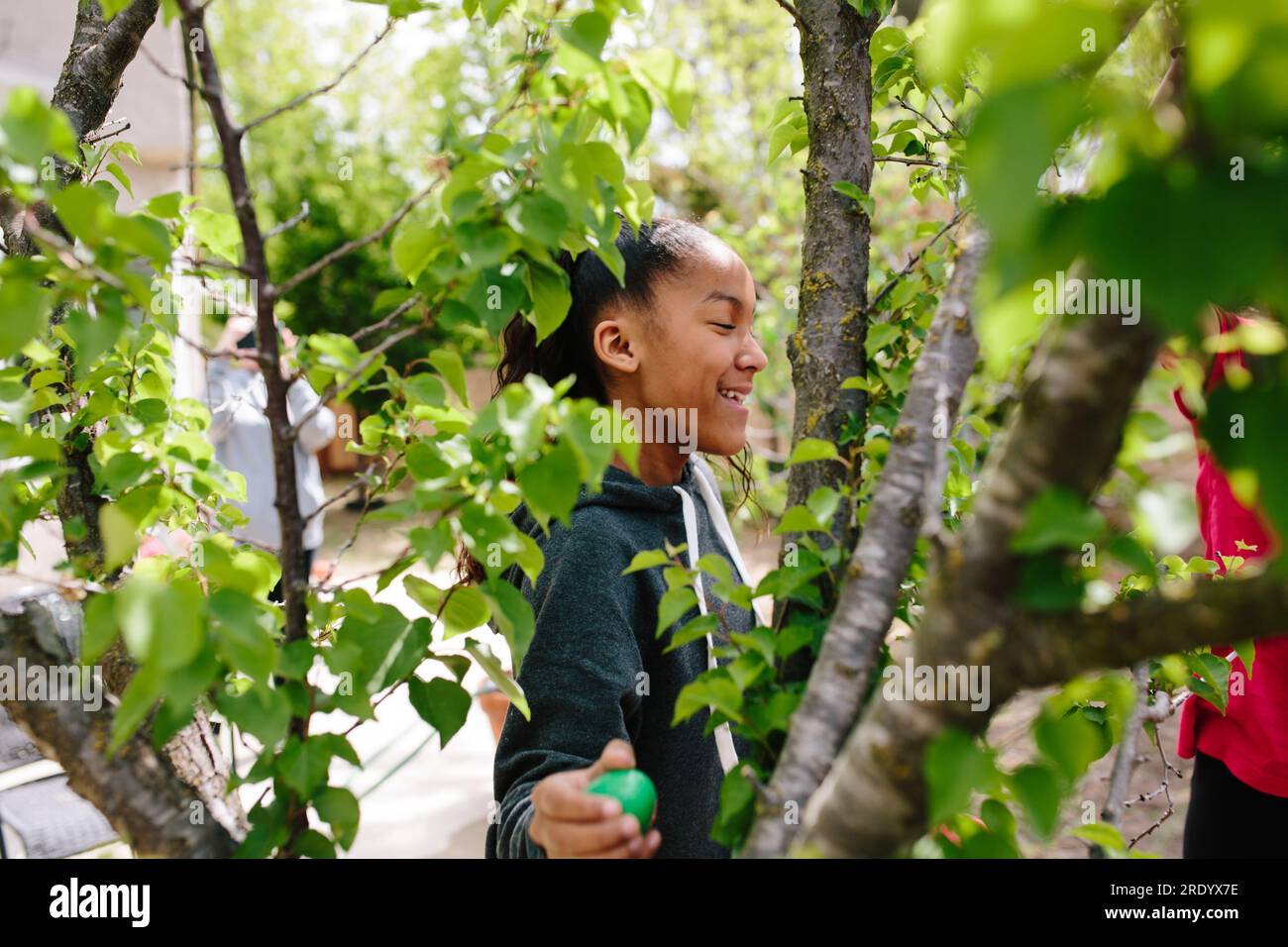 Foto del profilo di una ragazza che trova un uovo di pasqua di plastica in un albero Foto Stock